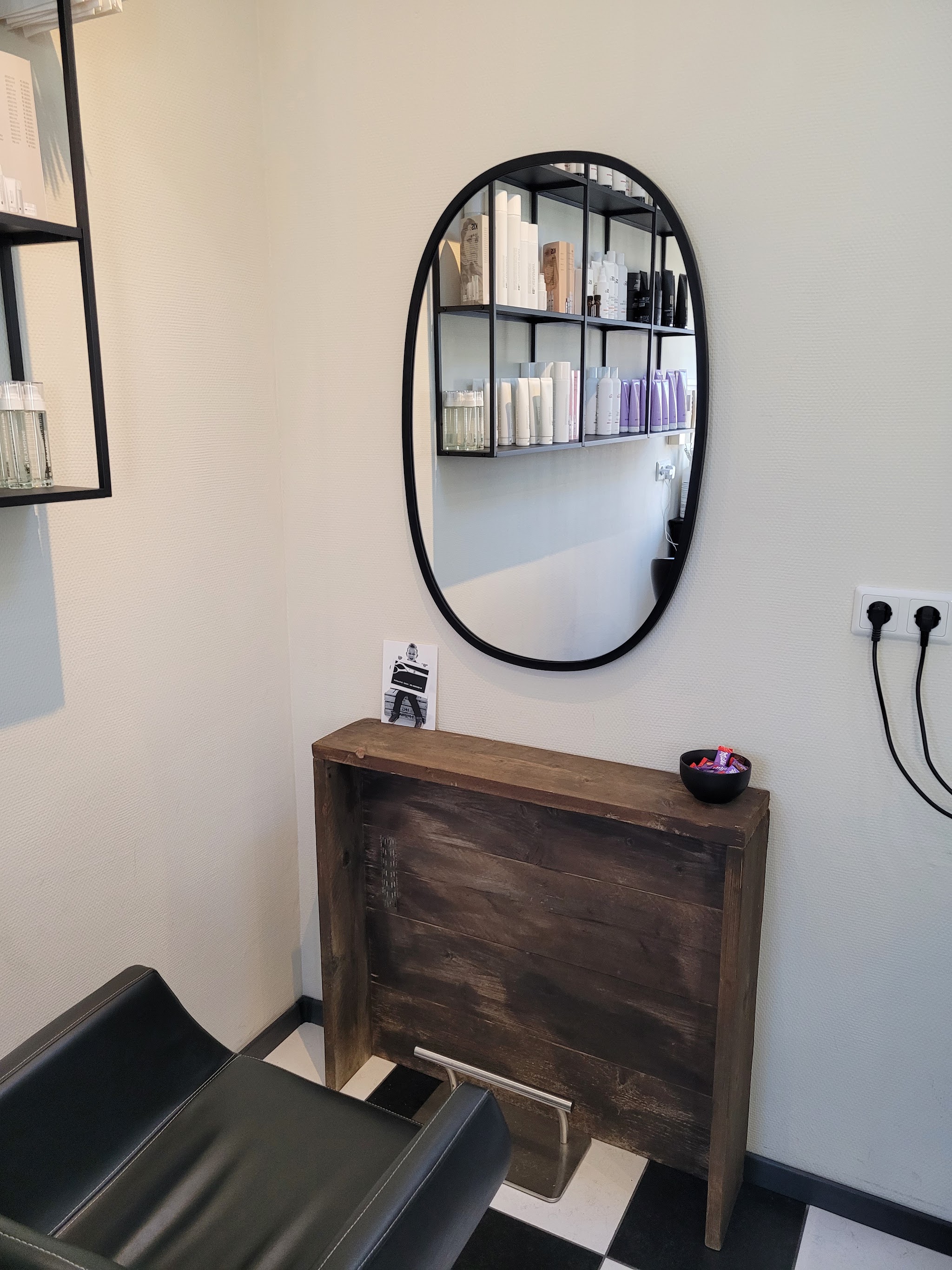 Kaptafel met een ovale zwarte spiegel boven een houten console in de salon