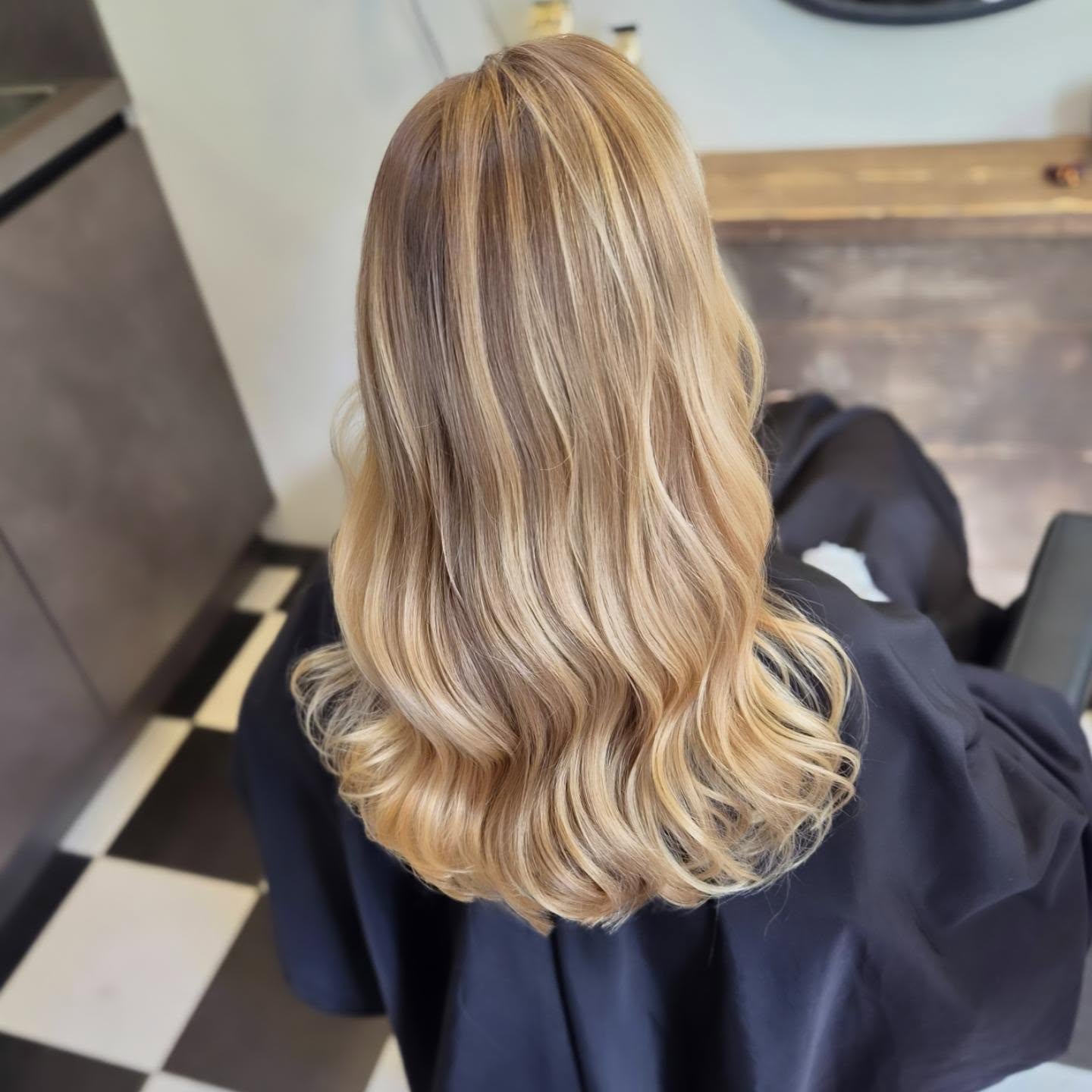 Lang blond haar met highlights en losse slagen, van achteren gezien in de salon