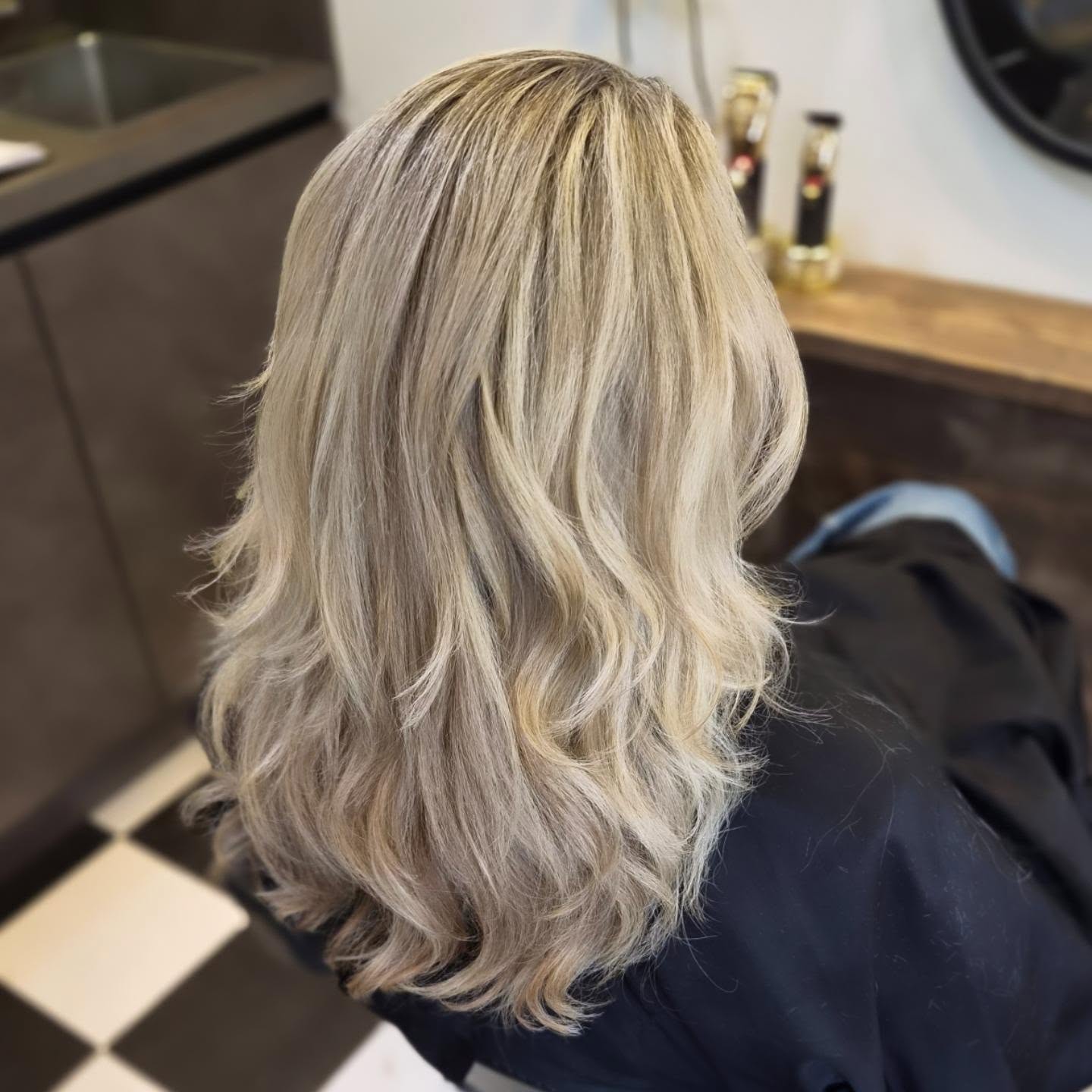Asblond haar met babylights, highlights en veel lagen, van achteren gezien