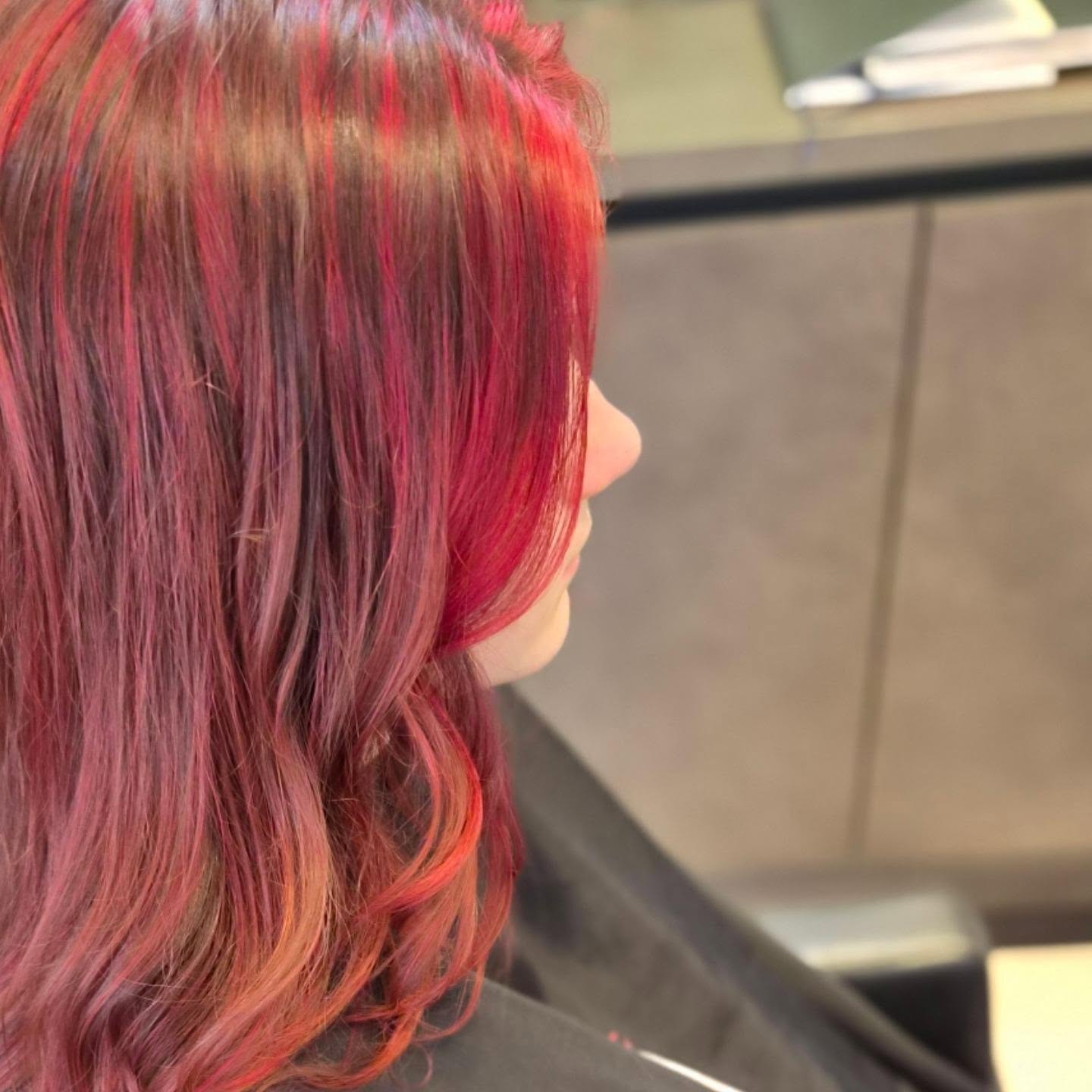 Halflang haar in fel rood en roze, van opzij gezien