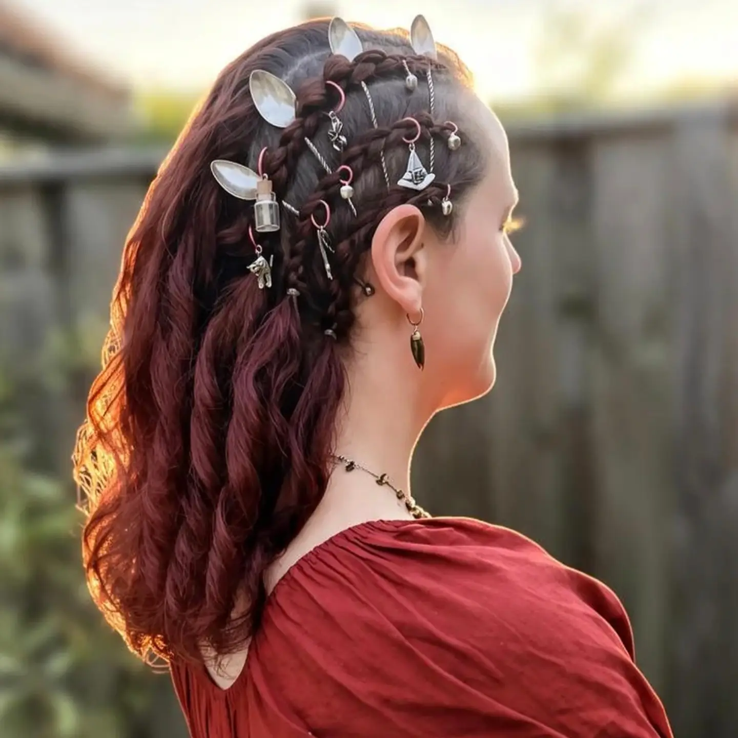 Opgestoken festivalkapsel met gevlochten rood haar, theelepels en haarpiercings, van opzij